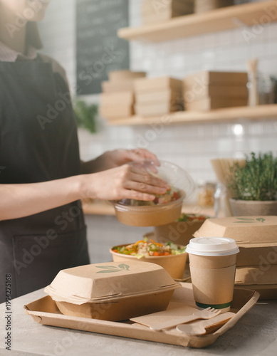 A woman prepares food and drinks on a wooden tray in a kitchen