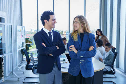 Two businessman and businesswoman partners  in suits smiling standing Talking Multiethnic workers with in company workers Group of business people and support Teamwork in meeting room at office