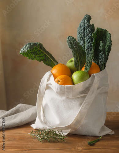 Fresh produce spills out of a reusable bag on a wooden table indoors