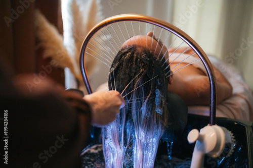 Photos Close up of professional hands applying water and massaging scalp in spa
