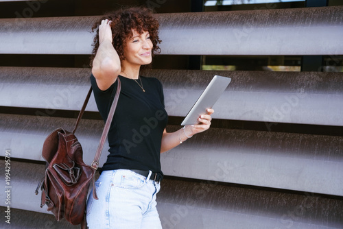 Female designer analyzing concepts on tablet against building facade in natural daylight