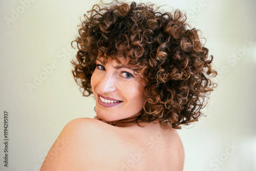 Joyful face glance. Charming actress with soft smile and illuminated shoulders in studio