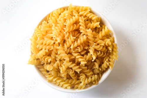 top view of fusilli pasta in a bowl on a white background