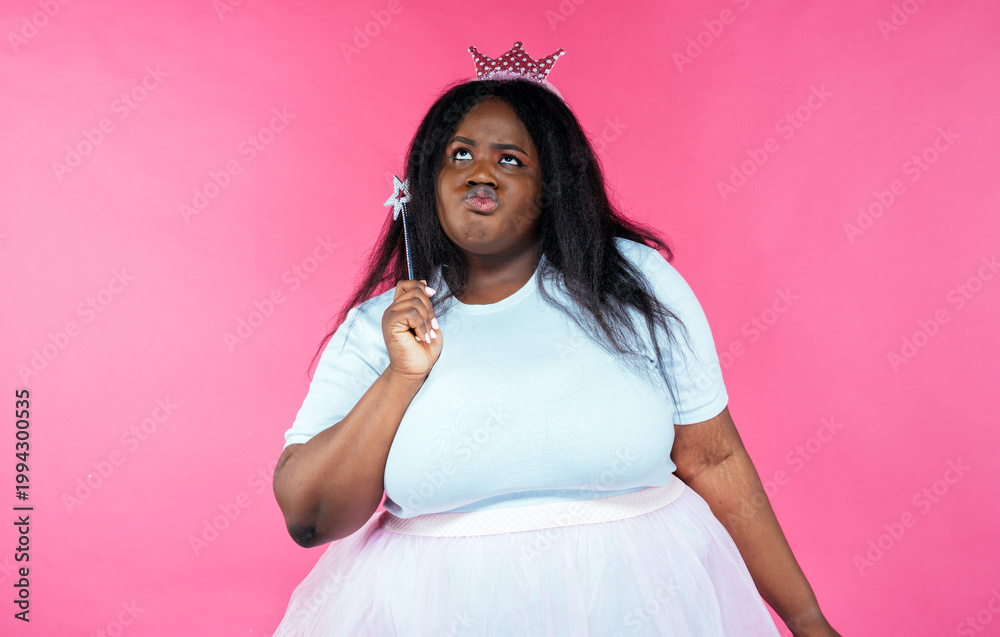 Fototapeta premium Image of a beautiful woman posing in a fairy costume on a pink background