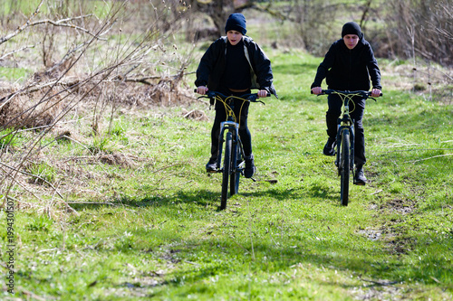 Two boys biking on a grassy trail, enjoying a sunny day outdoors. A fun adventure on two wheels