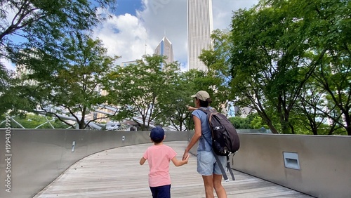 Fotografie Mother and child enjoying a family day out, walking on a pedestrian bridge in mi