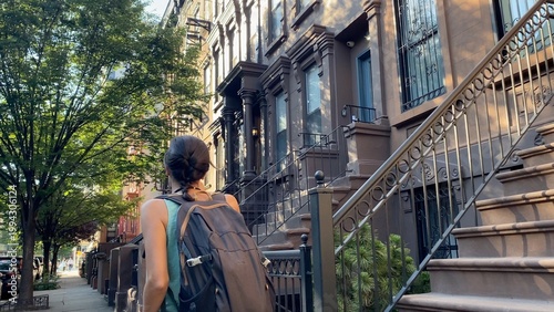 Tableau sur toile Young woman walking along a tree-lined street in harlem, new york city, explorin
