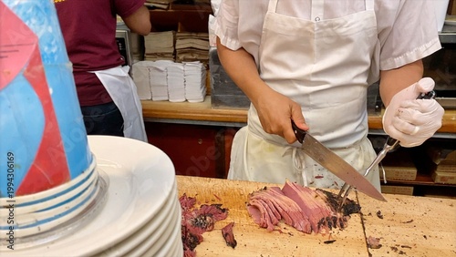 Schilderij op canvas Chef slicing hot pastrami meat by hand on a wooden cutting board, preparing a cl