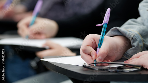 Foto Young woman taking notes at a desk in a college lecture hall