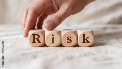 Hand Arranging Wooden Cubes Spelling 'Risk' on Fabric Surface