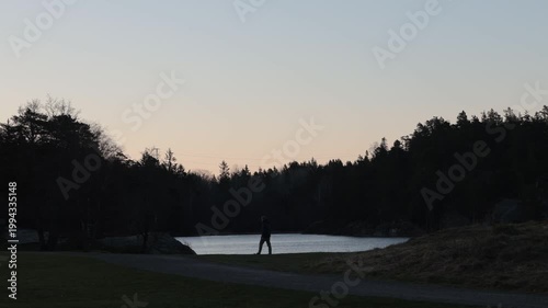Stockholm, Sweden A man walks through the Nacka Reservatet wilderness in the early dawn past a small lake. 