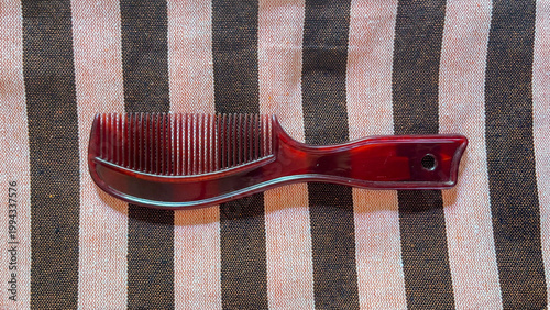 Cuadro en lienzo Brown tortoise shell hair comb on striped beige and black fabric