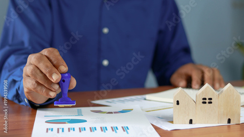 Canvastavla Businessman stamping real estate documents beside wooden house models, represent