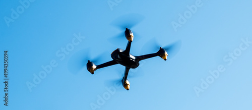 Industrial drone flying in clear blue sky. Modern technology for game, delivery or work.