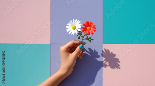 Hand holding a flower bouquet featuring a white daisy and a red flower against a colorful geometric background of pastel squares in pink, purple, and teal