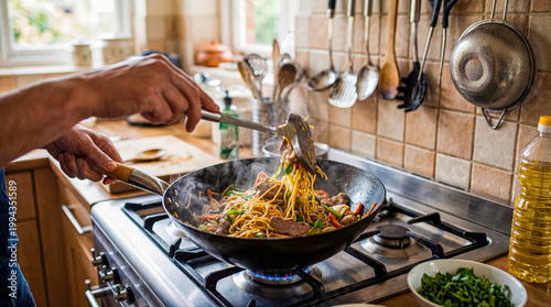 Photos Chef stir-frying savory noodles with meat and mixed vegetables in a hot wok on a kitchen gas stove