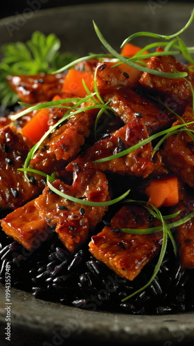 Glazed tofu cubes over black rice with green onions and sesame seeds. Asian-inspired vegetarian dish in dark bowl. Healthy plant-based meal concept for vegan cuisine and wellness. vertical format
