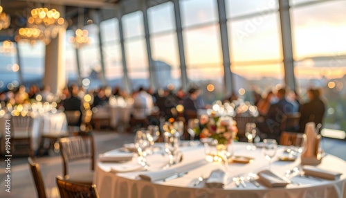 Elegantly set dinner tables in a high rise ballroom overlooking a city skyline during a beautiful golden hour sunset