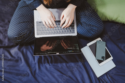 top view asian woman in classic blue pajama cloth work from home with serious feeling and sit on her bed for protect corona or covid-19 virus