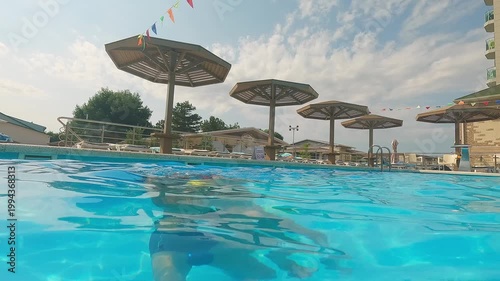 Happy family swim and play in blue hotel pool. Father fun throw little daughter into water. Summer vacation travel