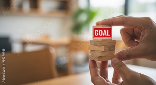 Hand holding wooden blocks spelling 'goal' representing achievement and success in a blurred background