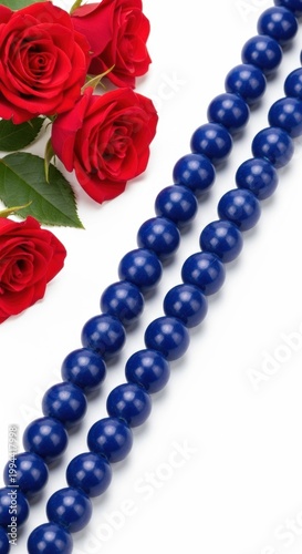 Elegant contrast of vibrant red roses and deep blue beaded necklace on a pristine background isolated on white background