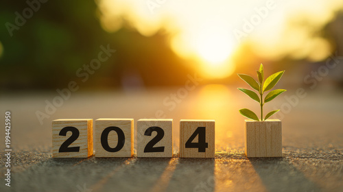 Year 2024 in wooden blocks cubes with growing plant at sunrise. New year 2024 hope concept.