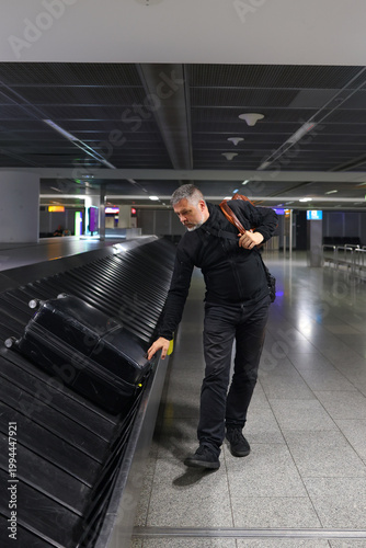 Passenger collecting suitcase at baggage carousel, journey and travel concept.
