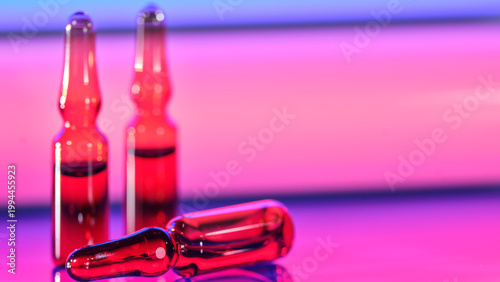 Red liquid in small glass vials placed on a colorful background during a studio shoot in the evening