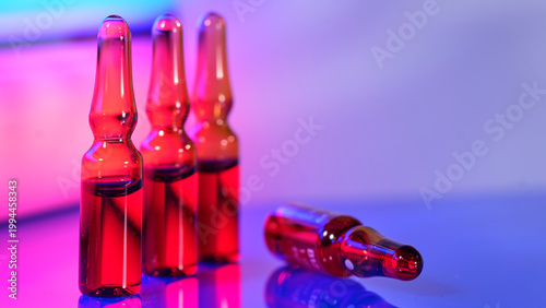 Red glass vials placed on a blue surface with colored lighting in the background at a modern location