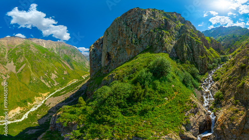 Majestic mountain valley with waterfall and rocky peak