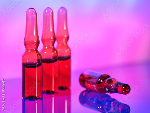 Three clear bottles with red liquid in a colorful setting around evening time
