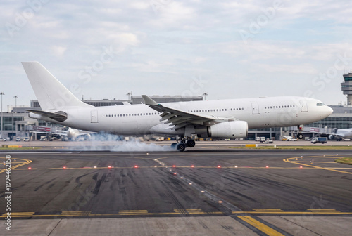 Passenger jet landing with tire smoke on runway at international airport