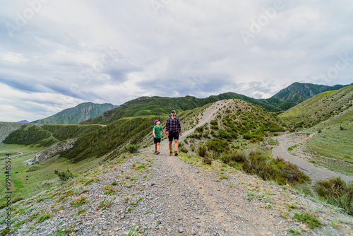 Fotografia father and son walking together on a scenic mountain ridge trail: family hiking