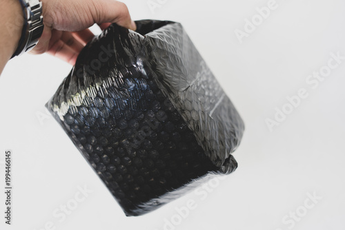A hand holding object wrapped in black bubble wrap
