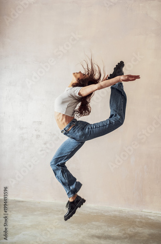 Young athletic slim energetic woman with dark long hair posing in the studio