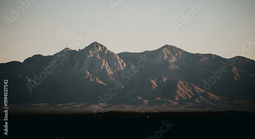 pixelated mountain range at sunset, digital art landscape, warm golden hour light casting long shadows across rugged peaks, serene, vast outdoor environment