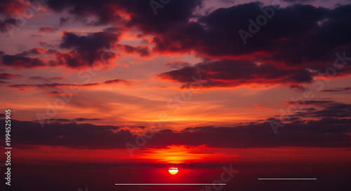 Dramatic sunset over the ocean with fiery red and orange clouds and a setting sun, evoking a sense of peace and awe.
