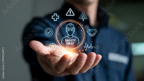 Industrial worker holding a glowing digital interface displaying safety first icons and professional health hazard symbols for modern workplace risk management