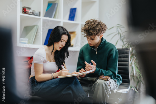 Foto Students sit together reviewing notes and writing in a notebook