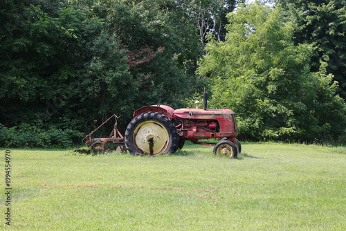 Vieux tracteur avec une herse dans un pré