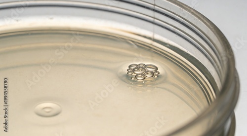 High angle close up of liquid in a glass jar with air bubbles on the surface