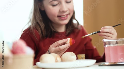 Little girl painting Easter eggs at home, 4K 10-bit cinematic footage of child decorating colorful eggs with watercolor brush for spring holiday, authentic lifestyle.