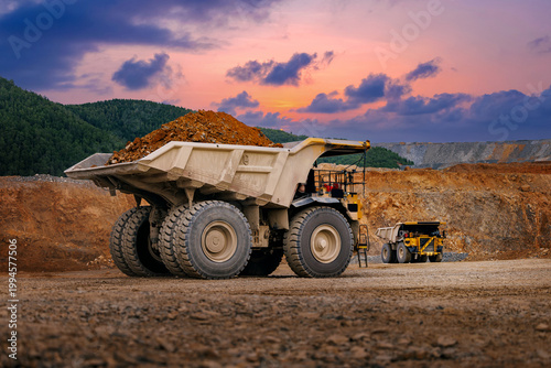 фотографія Large loaded haul truck in quarry with gold ore, sunset sky, mining industry con