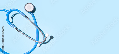 Stethoscope on blue background flat lay top view. Minimalistic medical concept, doctor's instrument for listening to breathing and heart. Space for text. International Doctor's Day