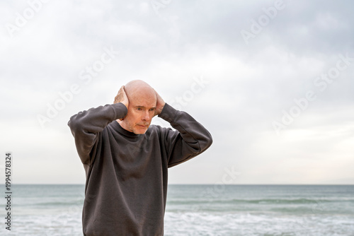 mature man standing with hands on head