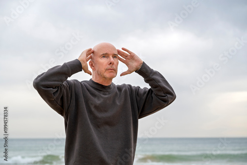 mature man standing with hands on head