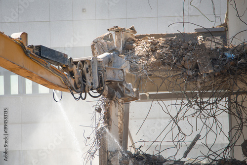 Demolition of reinforced concrete structure, gutting and renovation, hydraulic hammer dismantles building, caterpillar excavator machine at construction site