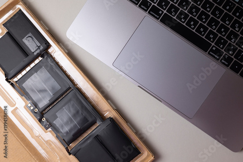 Modern Laptop Battery Repair Setup. Removable Battery Cell Pack On color Desk With Keyboard