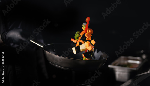 Bild auf Leinwand Colorful vegetables tossed in pan against dark background